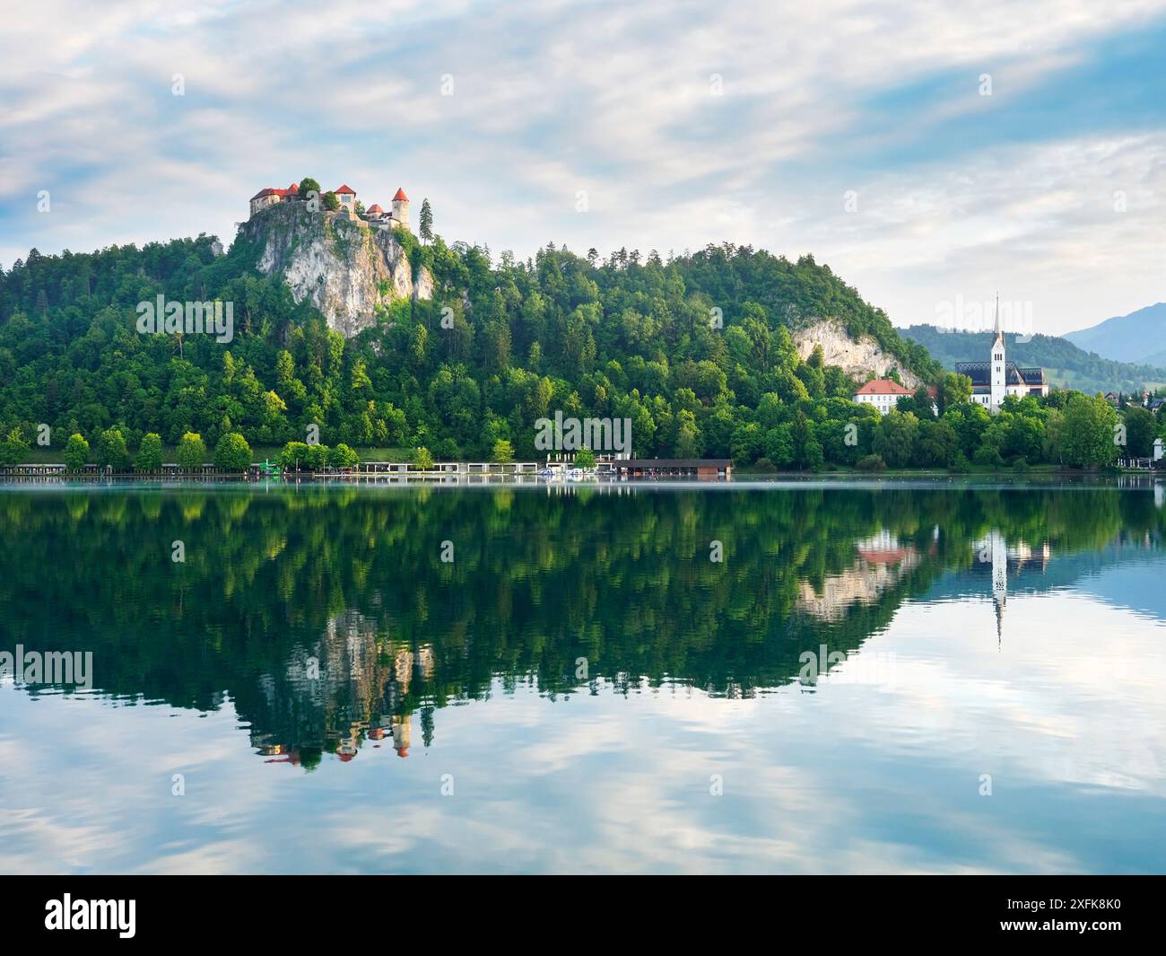 Bled Castle on cliffs reflected in Lake Bled early on a summer morning ...