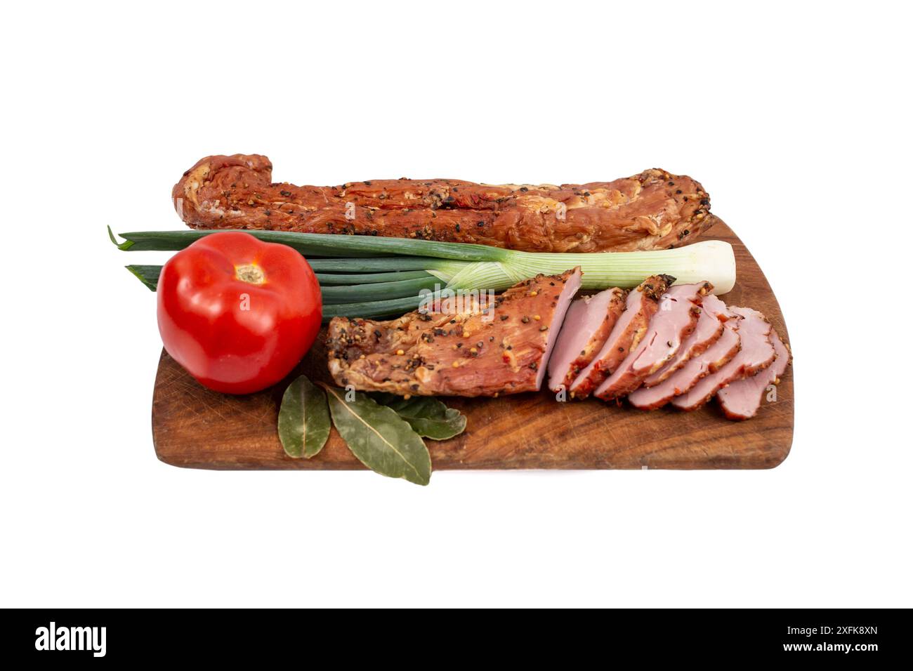 Pork meat tenderloin pastrami smoked and spiced, with thin slices, tomato and spring onion, on a wooden chopping board Stock Photo