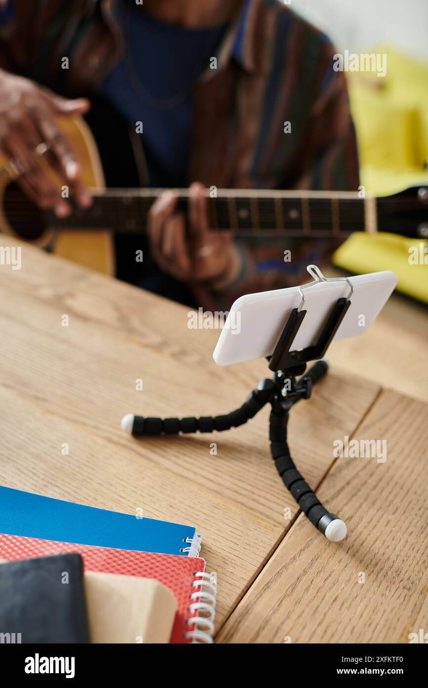 A man serenading with guitar, cell phone on table. Stock Photo