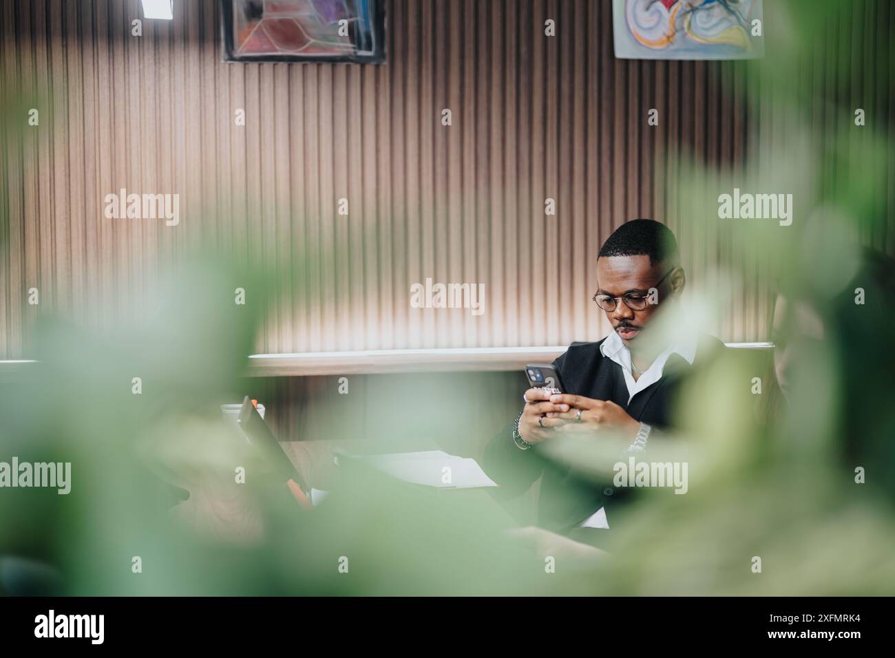 Professional businessman texting on smart phone in a modern office setting Stock Photo