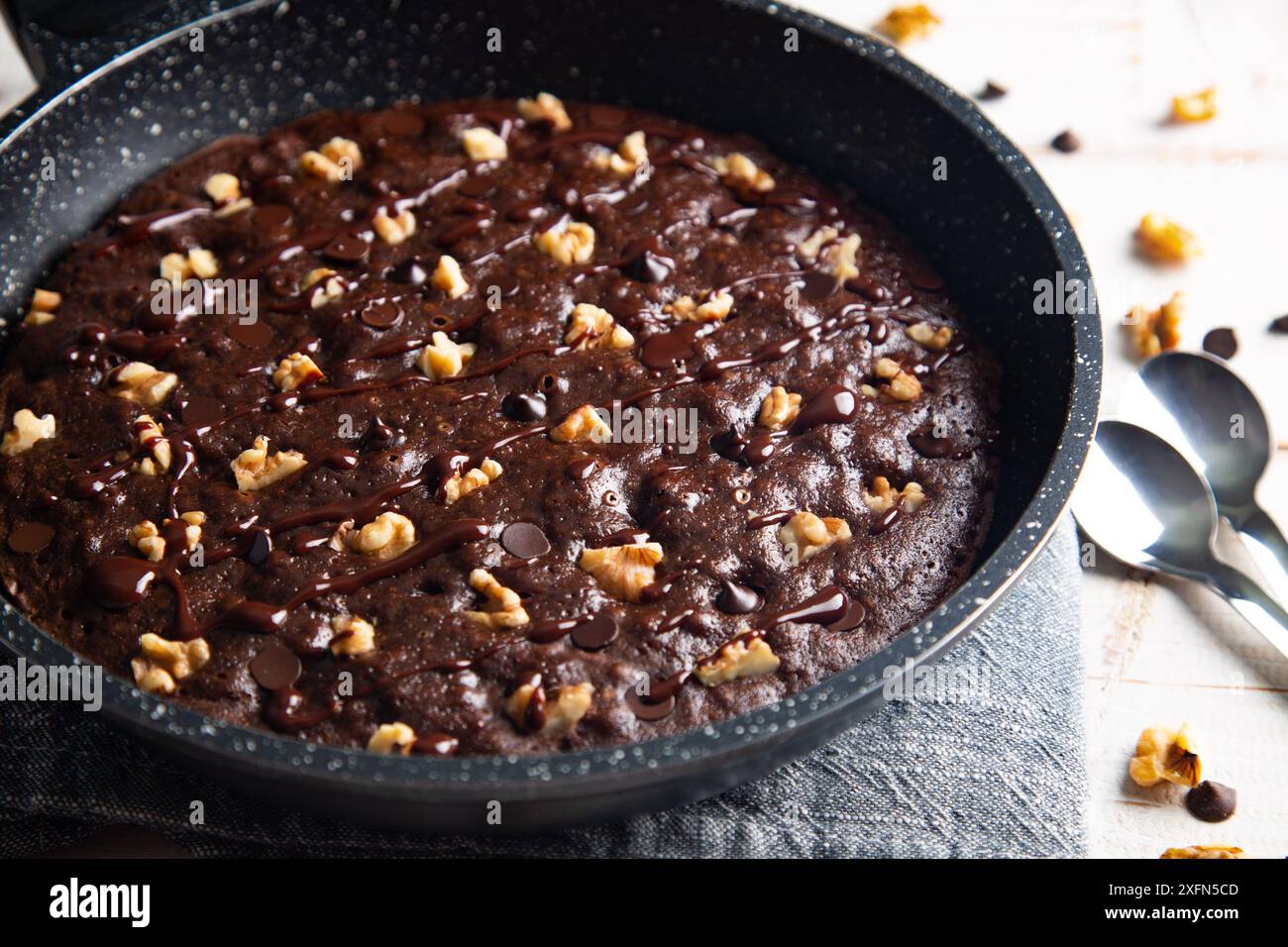 Homemade brownie cooked in a skillet, not baked, with nuts, chocolate chips on a white table Stock Photo