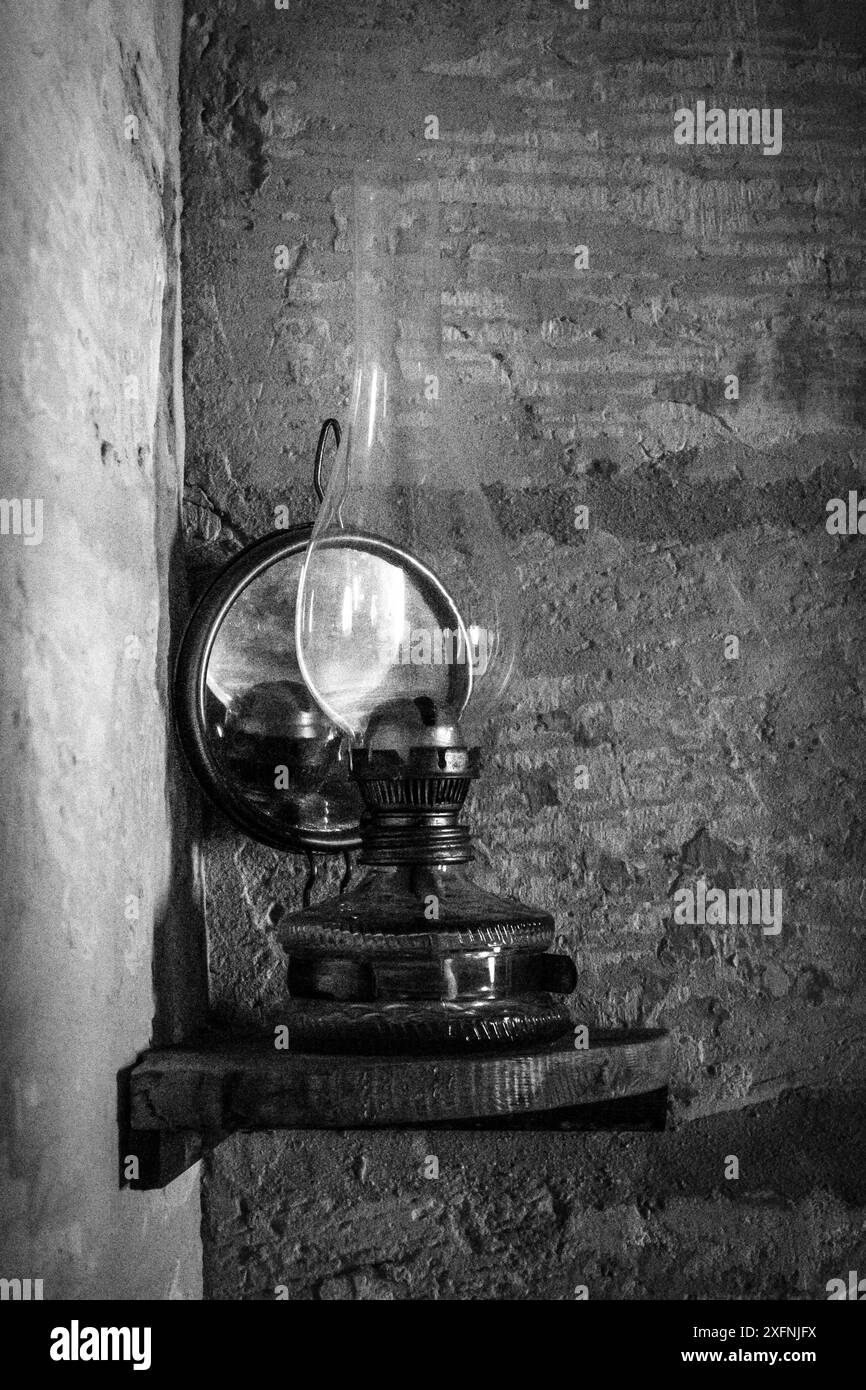 an old oil lamp against a wall in black and white Stock Photo