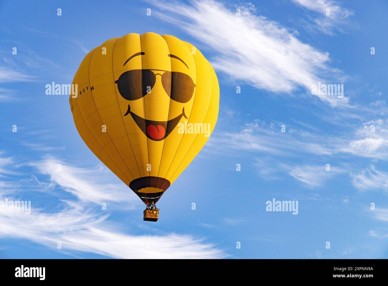 Yellow hot air balloon with a face with a big smile against a blue ...