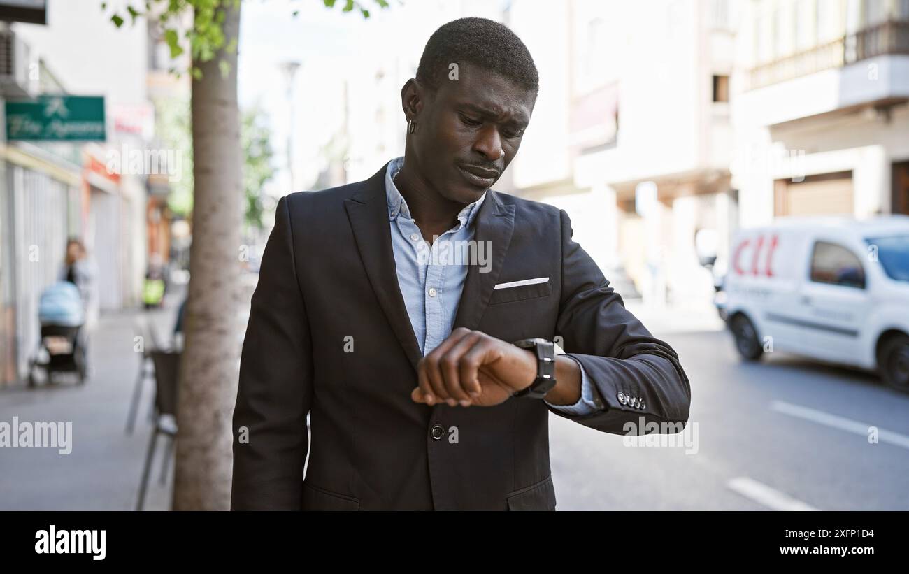African man in suit checking time on wristwatch on busy city street ...
