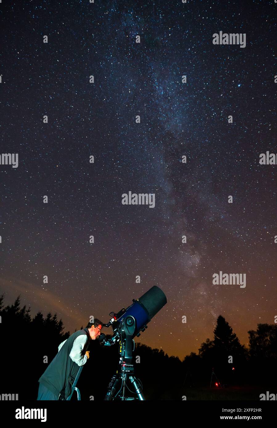 Man looking through a telescope at the night sky, Eifel Dark Sky Park, Eifel National Park, Germany, September 2016. Stock Photo