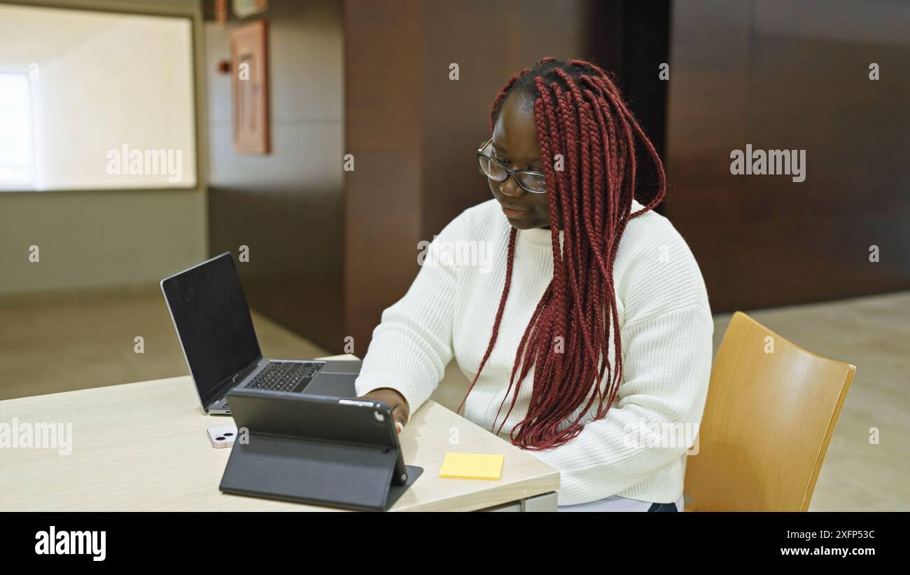 Focused african american woman with braids working on laptop at office ...