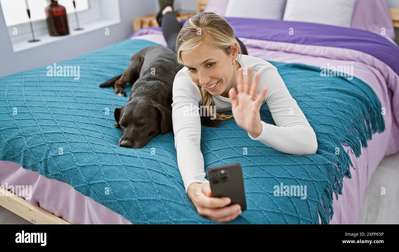 A young caucasian woman makes a video call with her black labrador ...