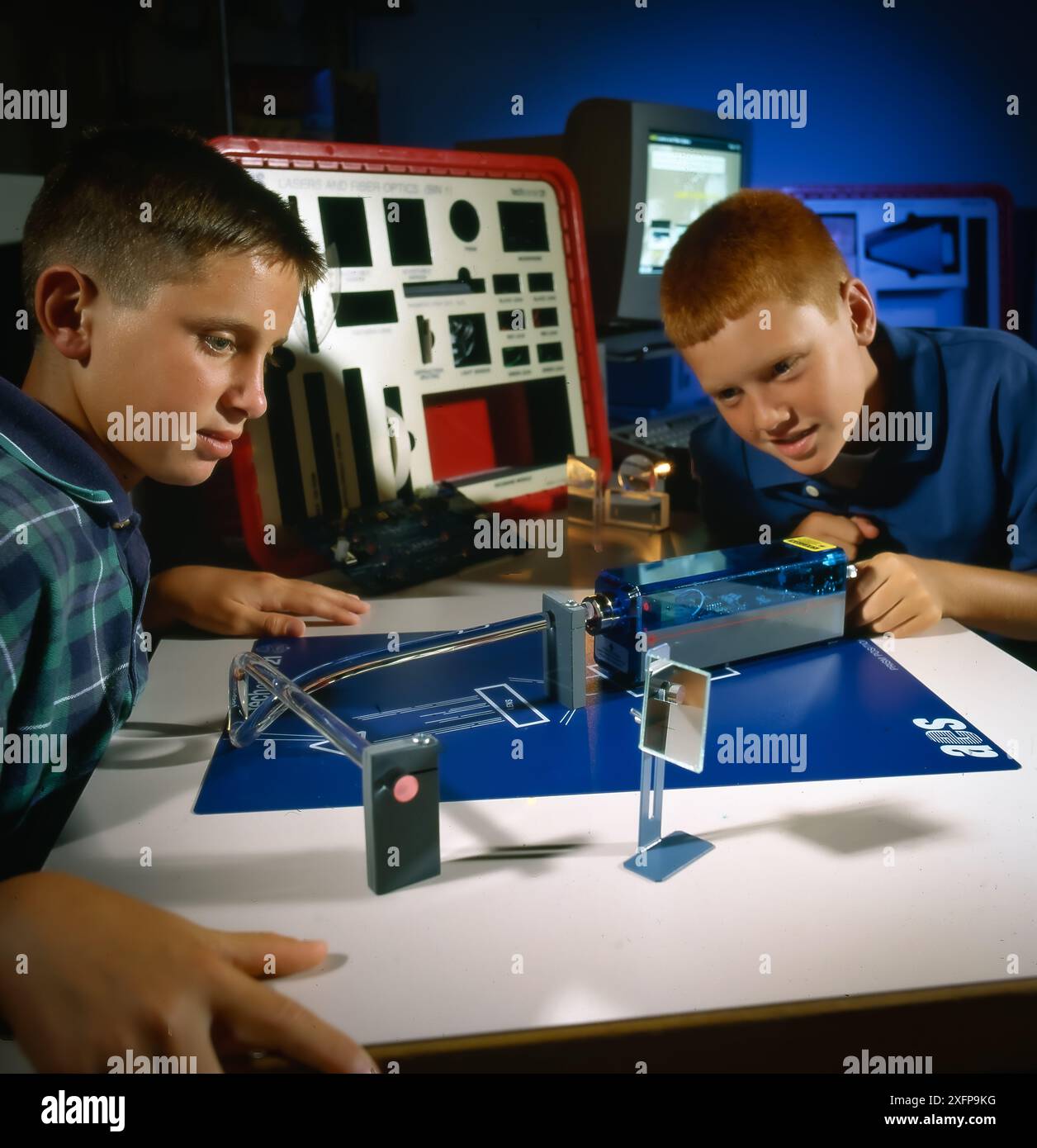 Two schoolboys experiment with an optics kit, observing laser light ...