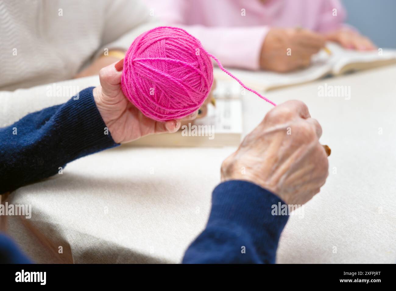 Close up of an old woman hands as she winds a woolen thread at nursing ...