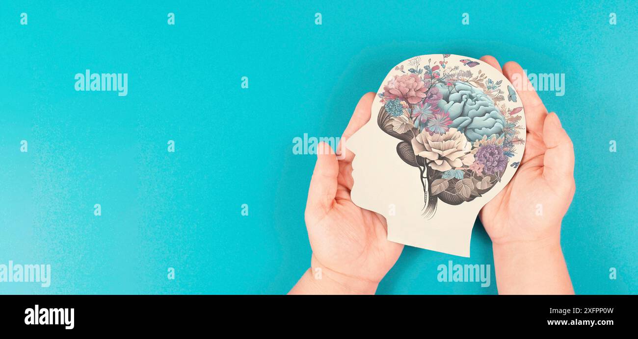 Hands holding paper head, human brain with flowers, self care and mental health concept, positive thinking, creative mind Stock Photo