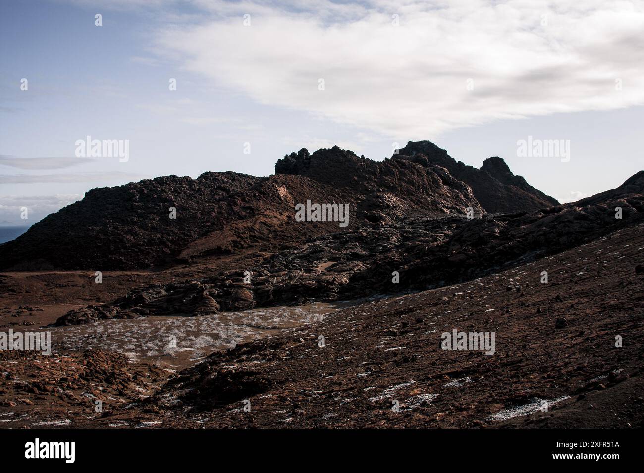 A stunning view of the Galapagos Islands' volcanic terrain under clear blue skies, highlighting the rugged beauty and geological features of this uniq Stock Photo