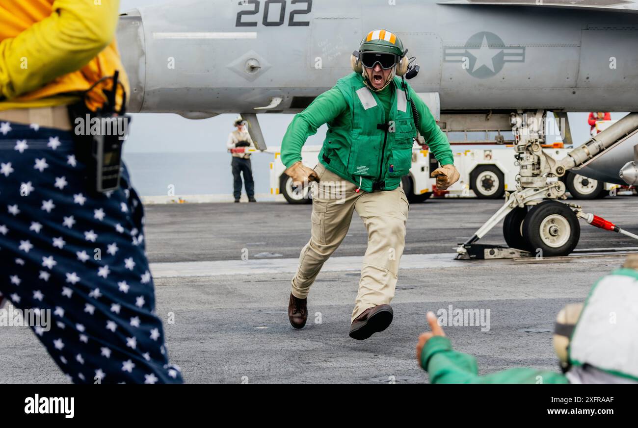 Chief Aviation Boatswain’s Mate (Launch/Recovery) Equipment Justin King, from Chanhassen, Minnesota, celebrates after preparing his last jet for takeoff before retirement on the flight deck of Nimitz-class aircraft carrier USS George Washington (CVN 73) while underway in the Pacific Ocean, July 3, 2024. George Washington is deployed as part of Southern Seas 2024 which seeks to enhance capability, improve interoperability, and strengthen maritime partnerships with countries throughout the U.S. Southern Command area of responsibility through joint, multinational, and interagency exchanges and co Stock Photo