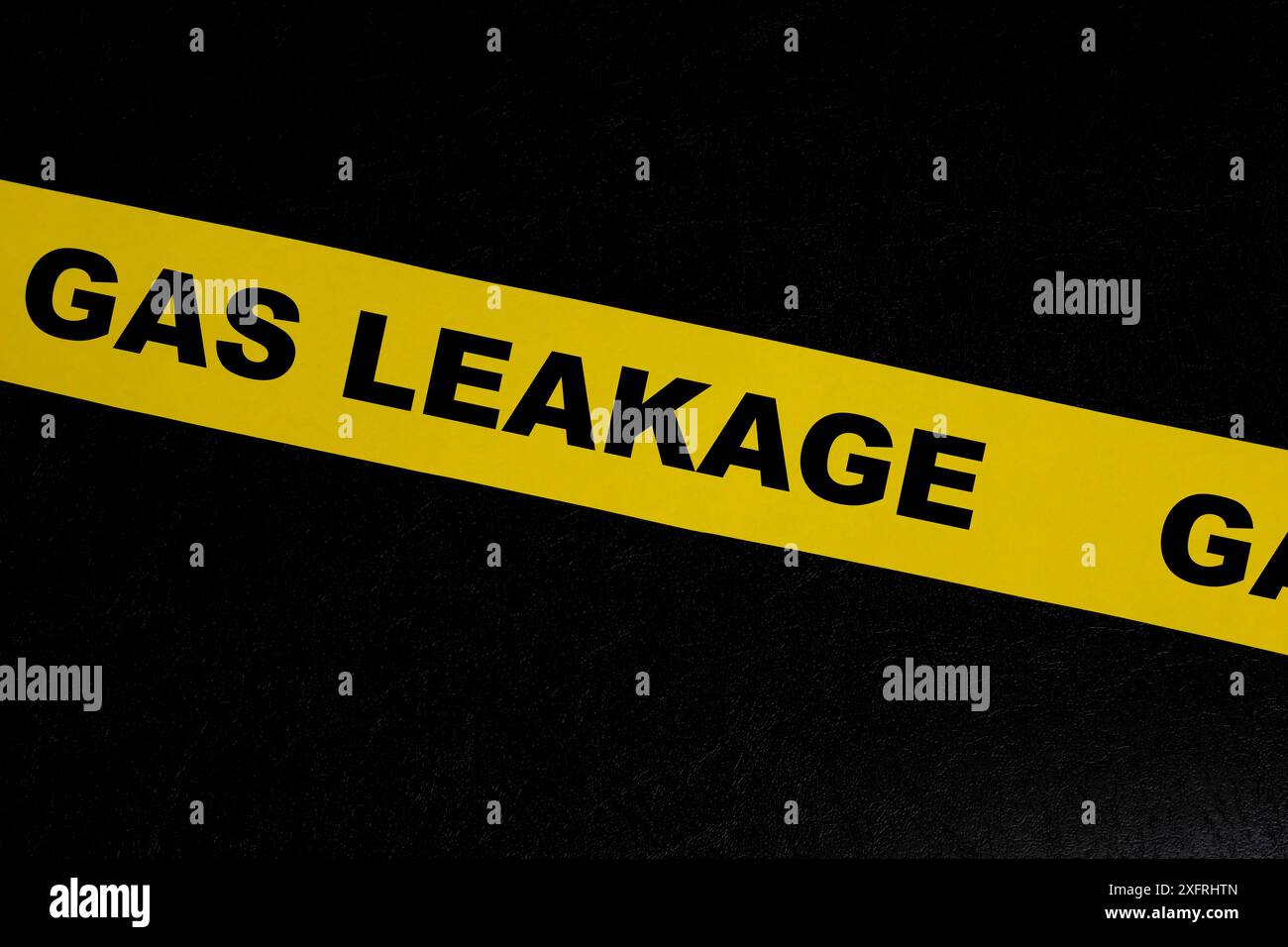 Gas leak or leakage caution danger and warning concept. Yellow barricade tape with word in dark black background. Stock Photo