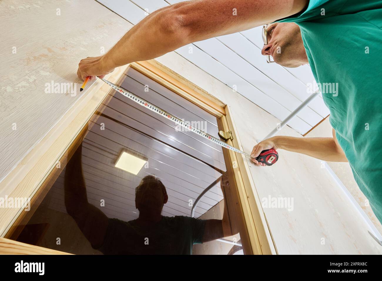 Measuring doorway to mark using tape measure holding piece in place and ...