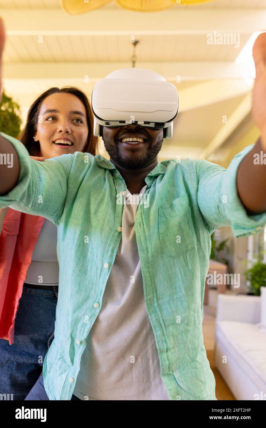 Using VR headset, man exploring virtual reality with friend at home Stock Photo