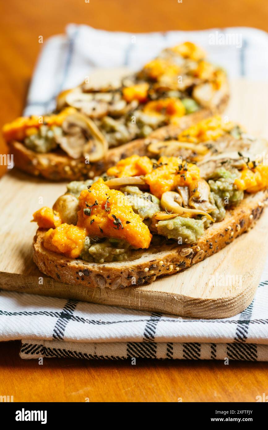 Cutting board with avocado toasts with mushrooms and vegan cheddar