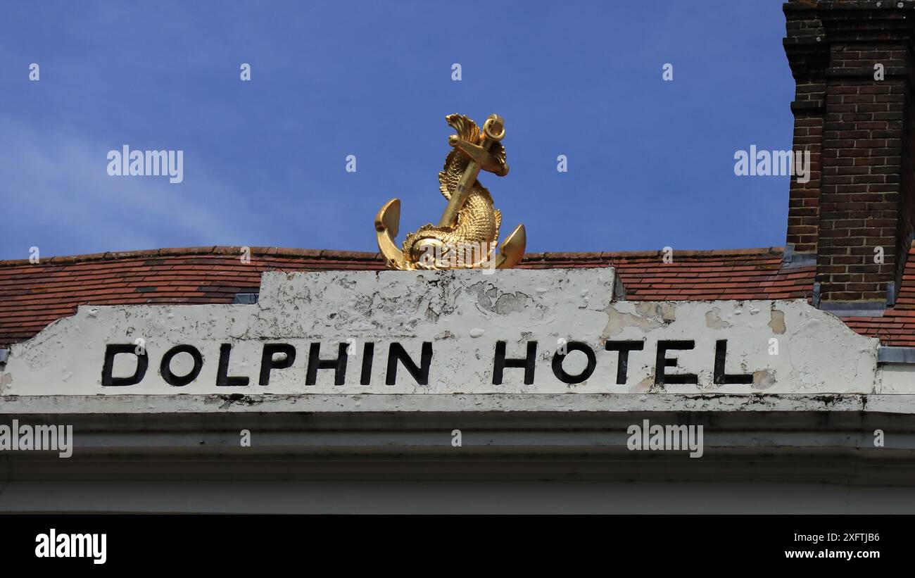 Chichester, West Sussex, England. 27 June 2024. Wide angle view of the fascia board for the Dolphin Hotel in Chichester, with a gold dolphin and anchor sculpture. Stock Photo