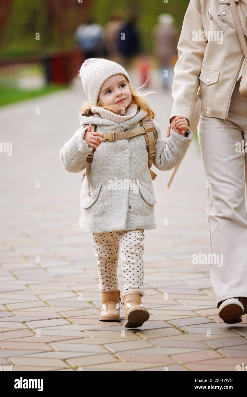 A happy little girl walks in the park with her mother by the hand Stock ...