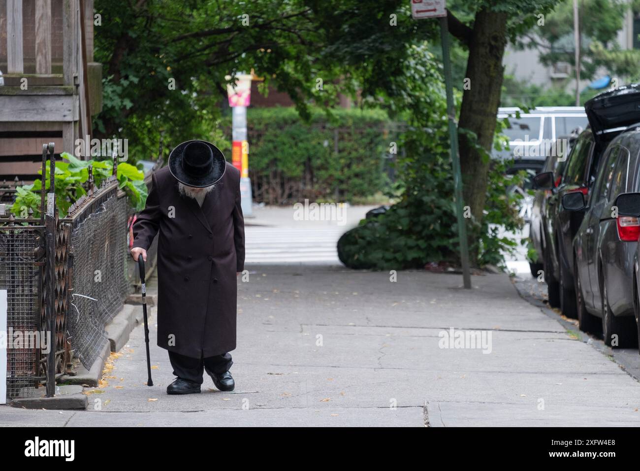 An older unidentifiable Hasidic Jewish man walks slowly to synagogue in Brooklyn, New York. Stock Photo
