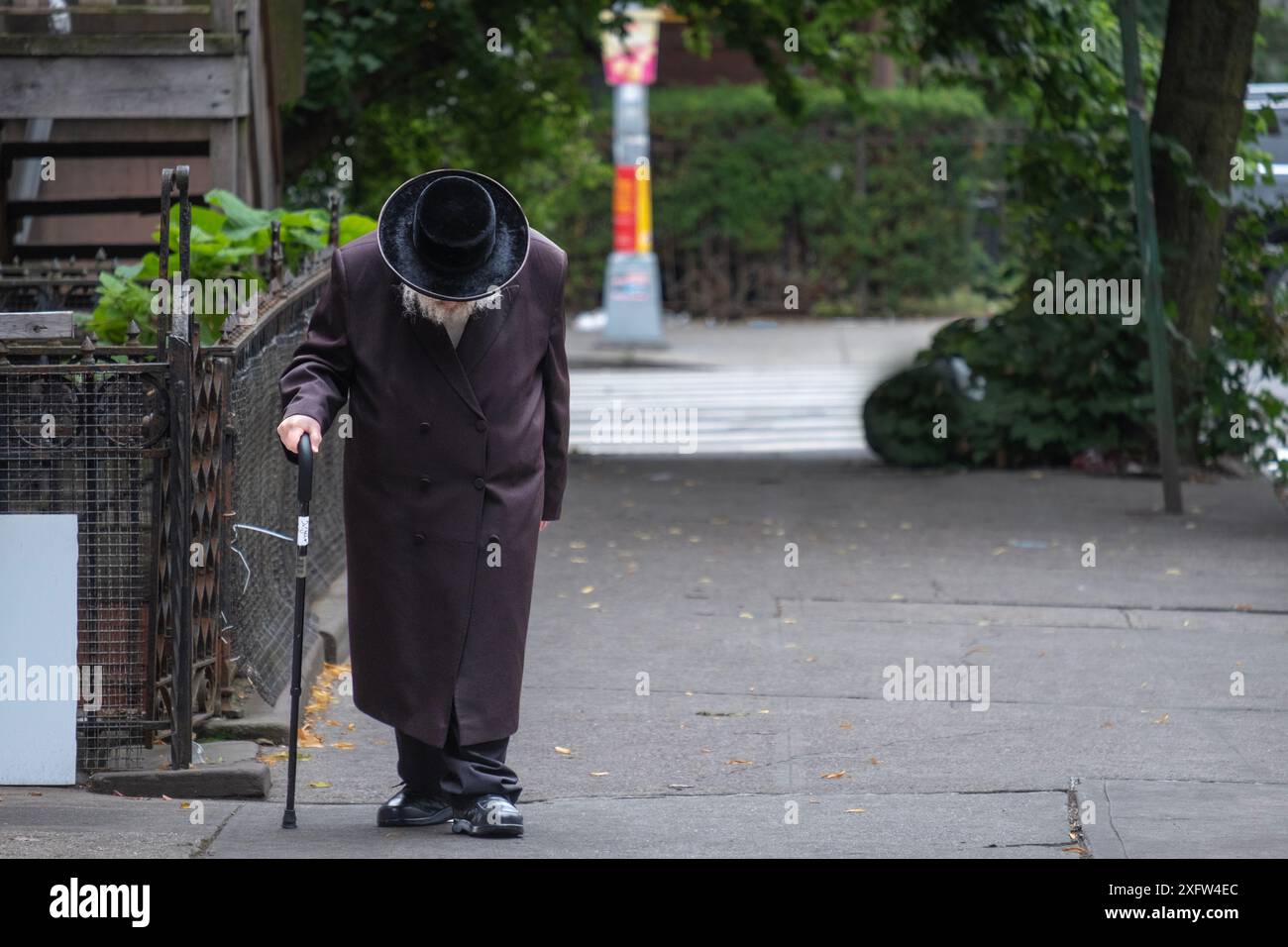 An older unidentifiable Hasidic Jewish man walks slowly to synagogue in Brooklyn, New York. Stock Photo