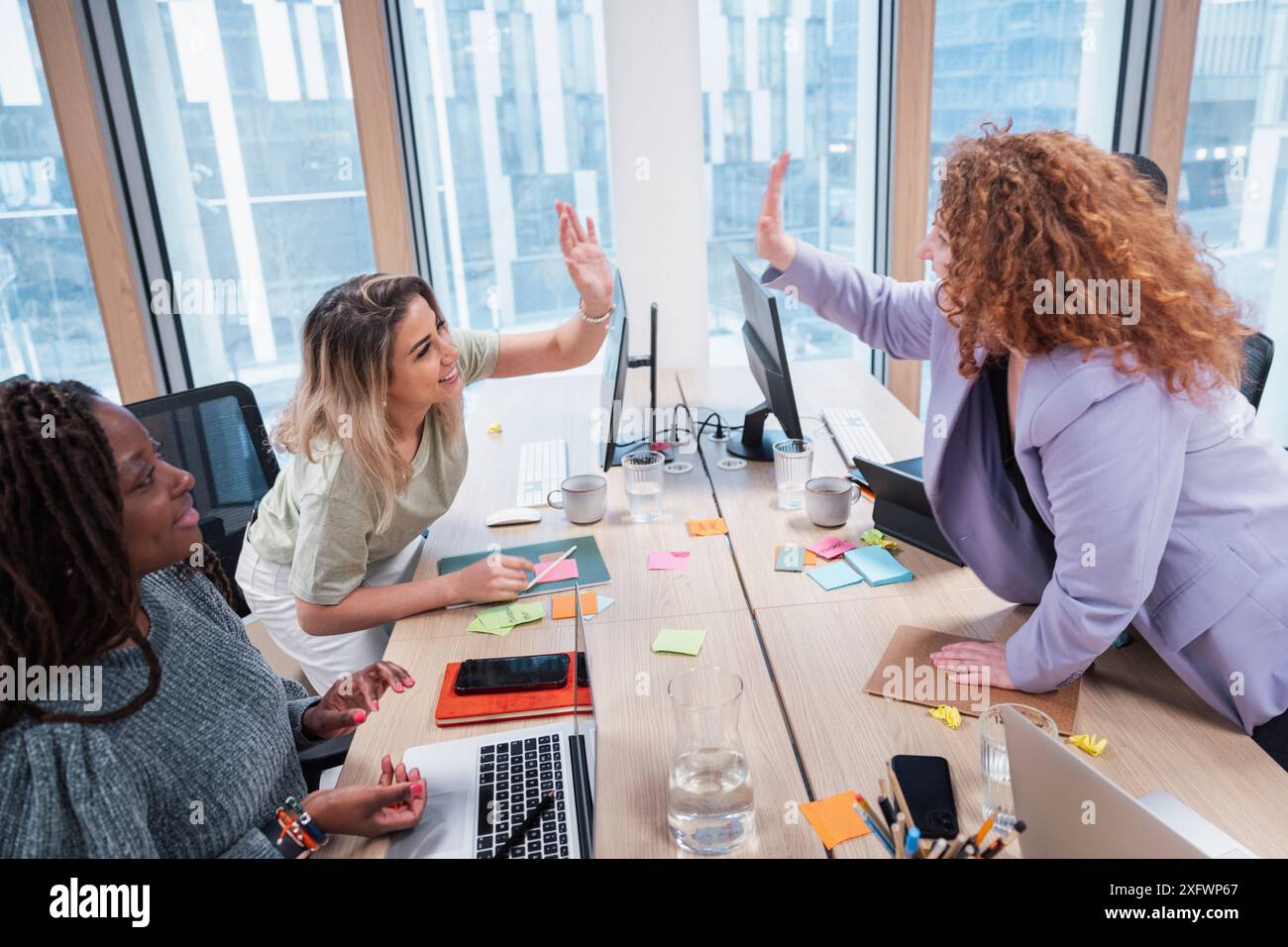 Female colleagues giving high-five while celebrating success in office ...