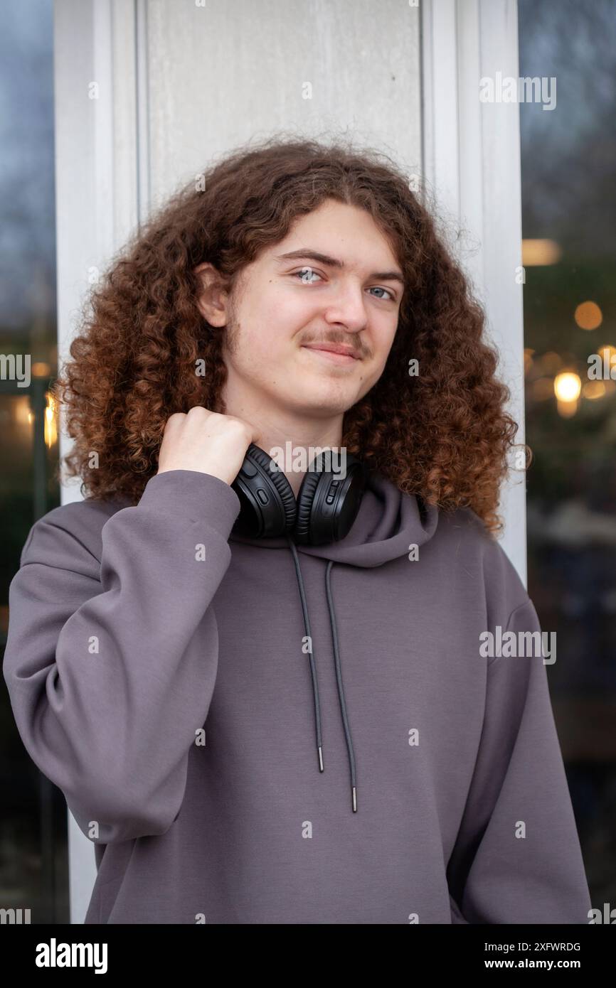 Portrait of young man with long curly hair in front of window Stock Photo