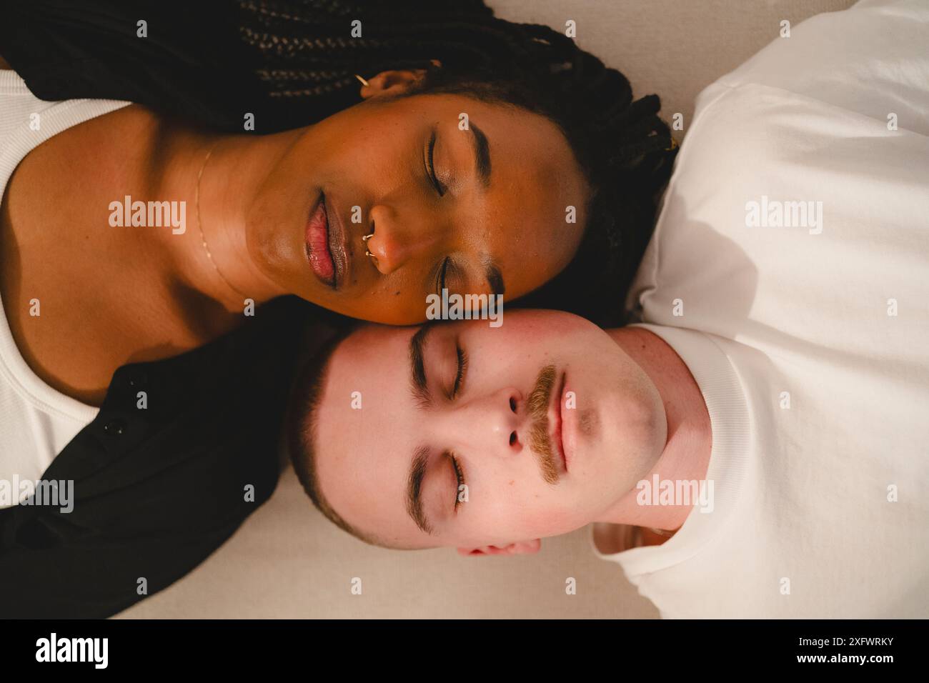 Young multiracial couple sleeping while lying next to each other at home Stock Photo