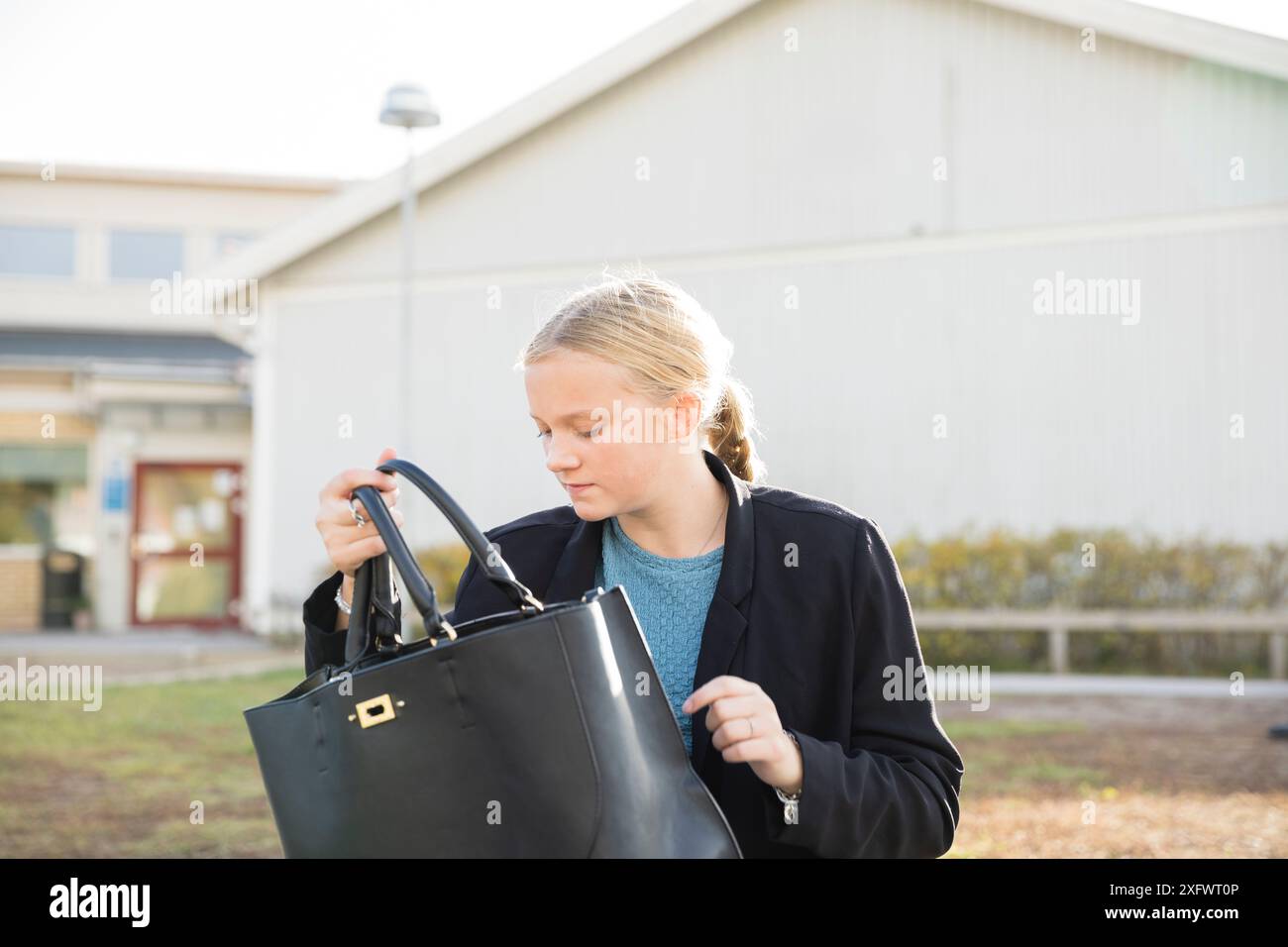 Teenage girl holding purse at schoolyard Stock Photo - Alamy