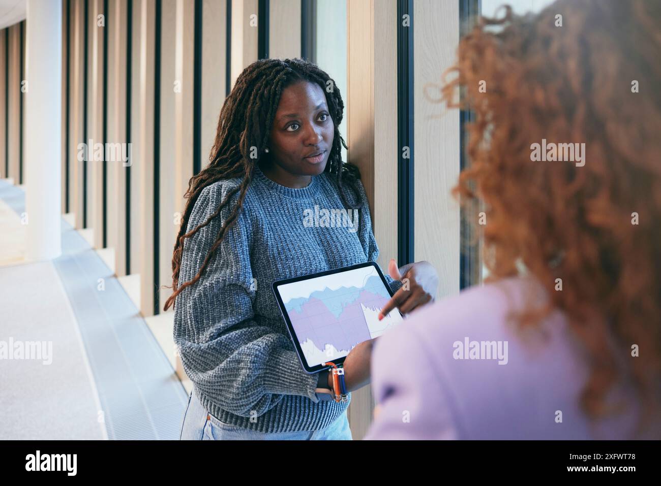 Young businesswoman explaining graph to colleague in office Stock Photo