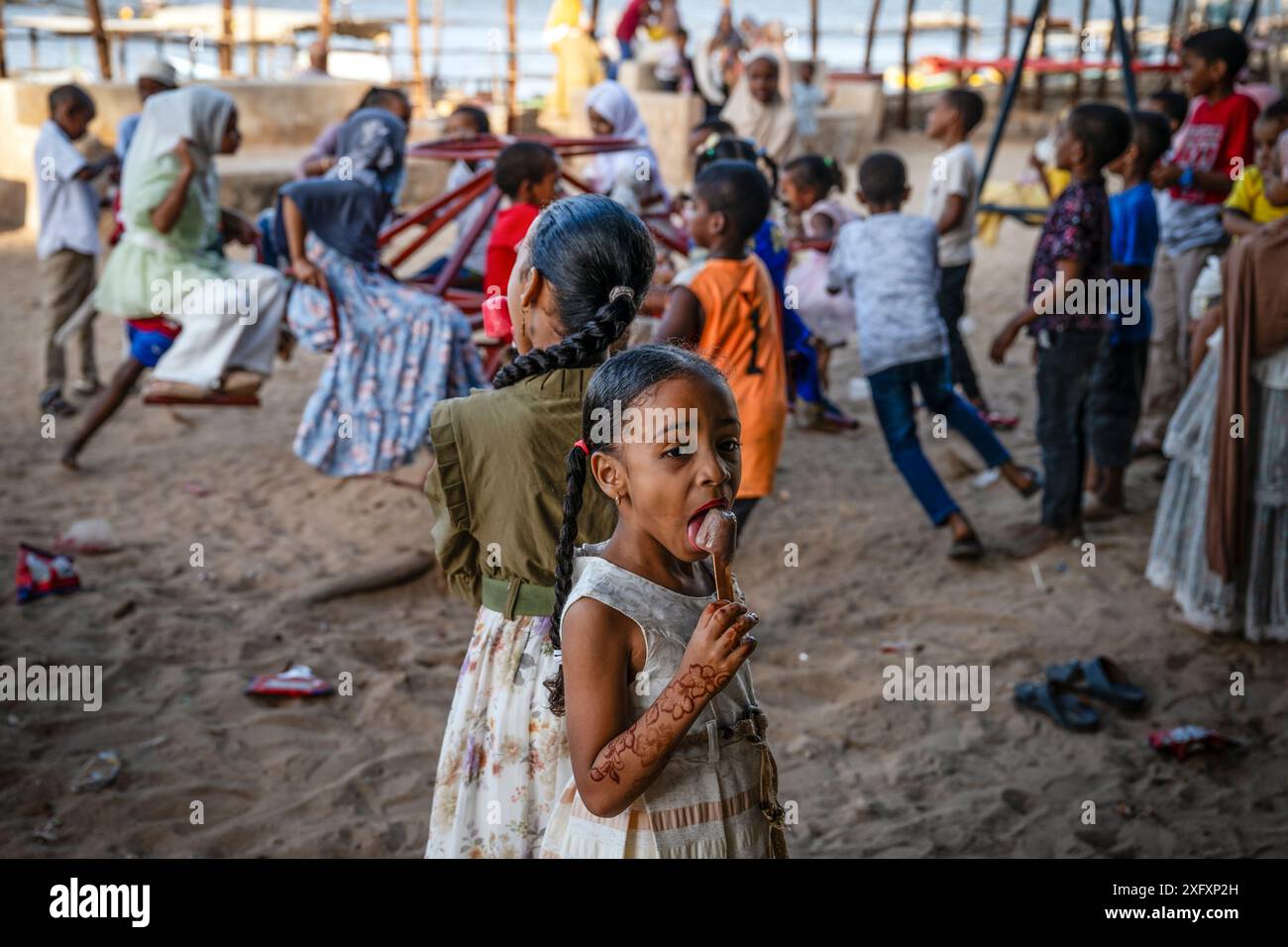 Children enjoy a playground on Shela Island off the coast of the Indian Ocean in Kenya. Shela is one of several islands in Lamu County. This area boasts some of the oldest and most well-preserved Swahili cultural settlements in East Africa. There are no cars on Shela and the town's calendar and daily schedule largely revolves around Islamic religion and culture. Stock Photo