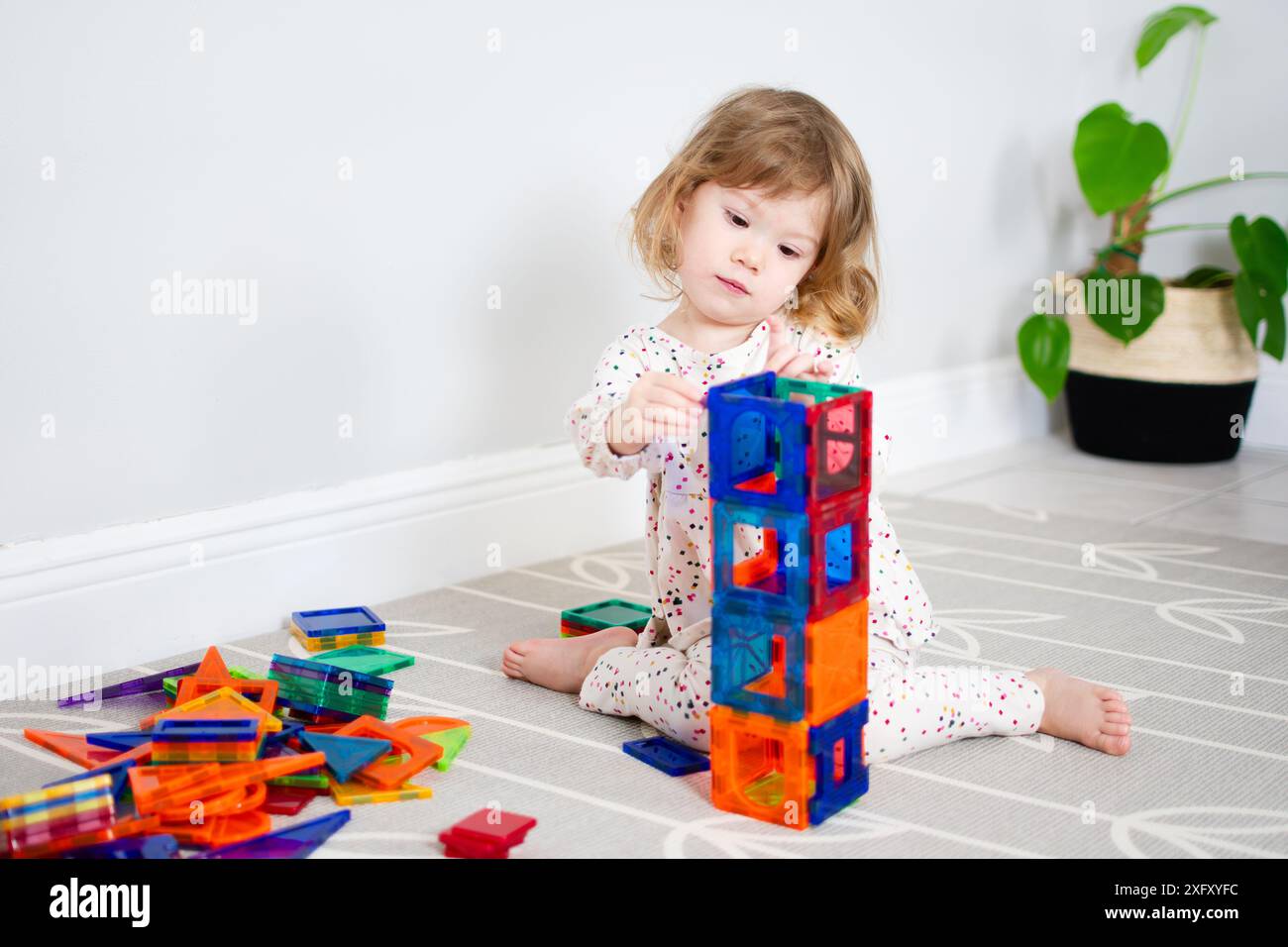 Little Caucasian Toddler girl playing with magnetic tiles. Magna tiles ...