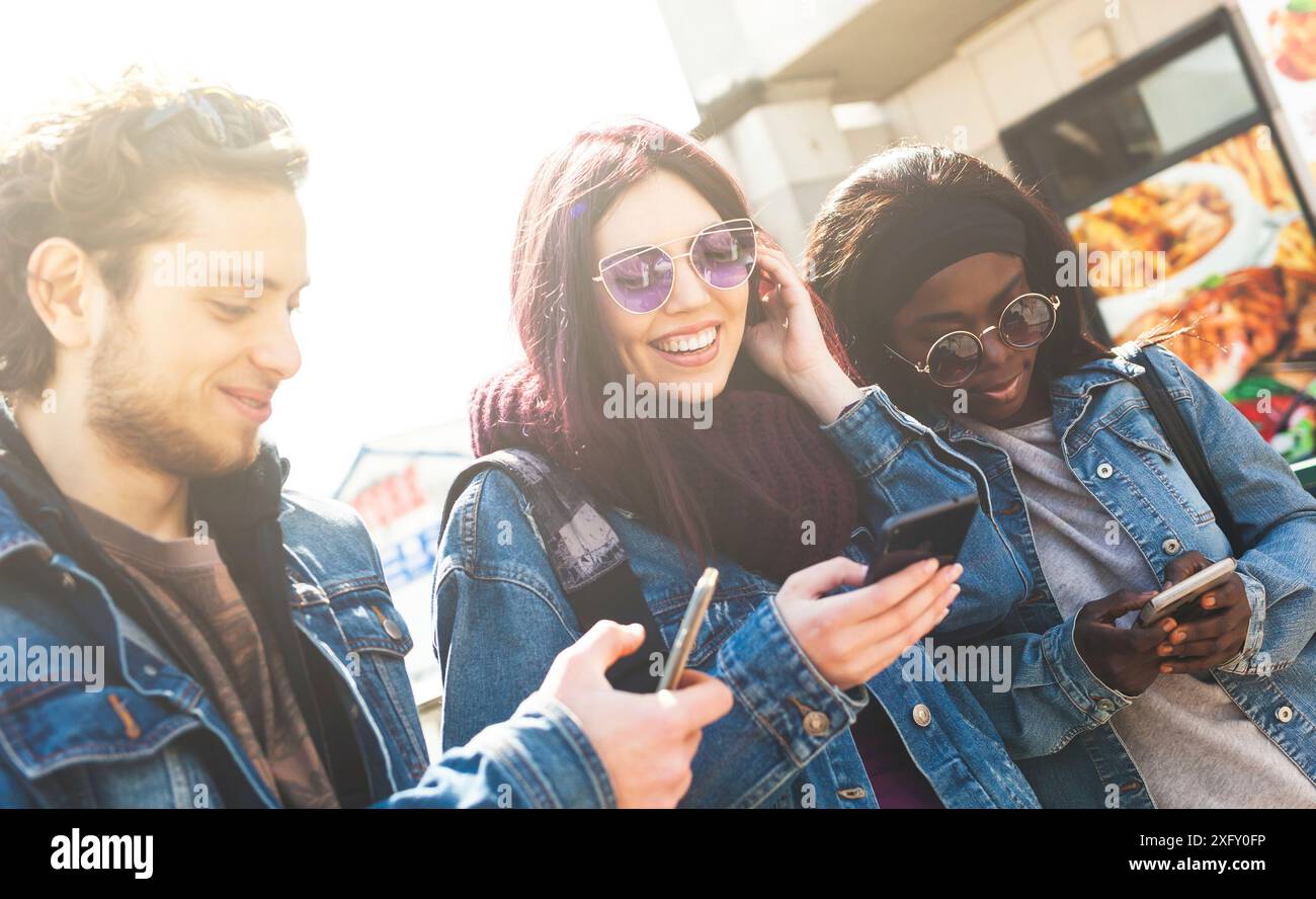 Multiracial friends having fun with smartphone in a spring day. Stock Photo