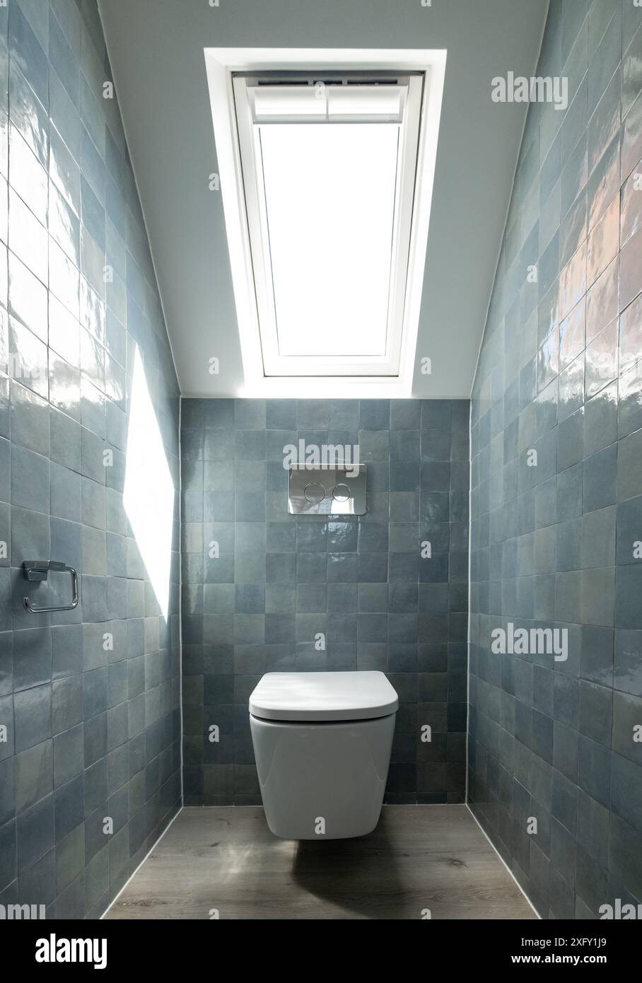 Small toilet in loft conversion making clever use of eaves in the attic.  Architect designed with blue porcelain zellige tiles, white wall hung toilet  Stock Photo - Alamy, image size:908x1390