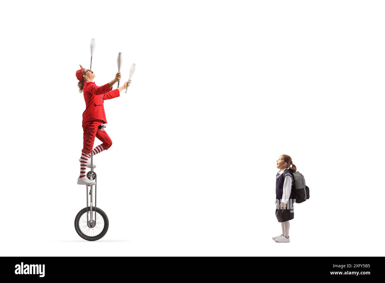 Schoolgirl watching an acrobat riding a unicycle and juggling isolated on white background Stock Photo