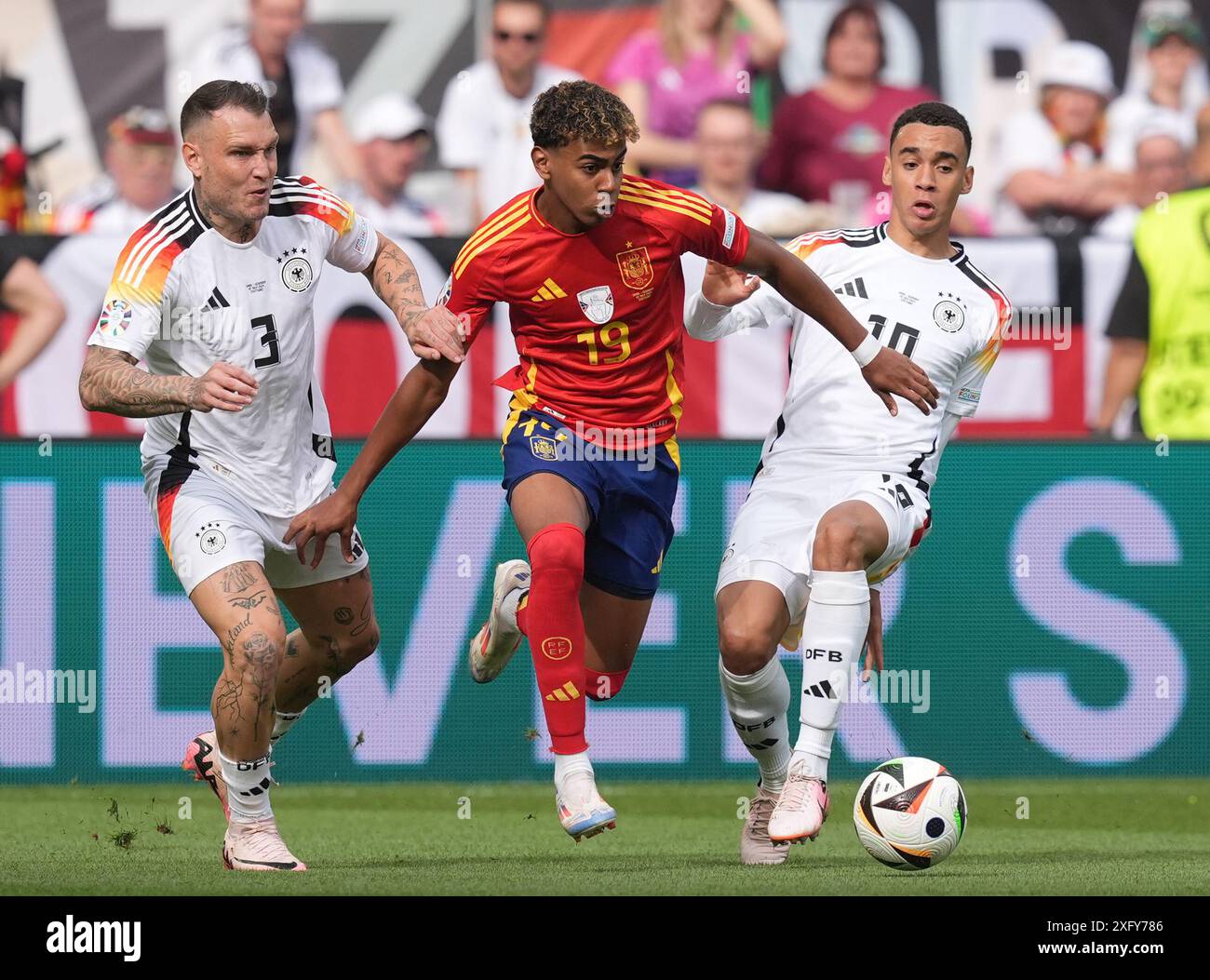 Spain's Lamine Yamal (centre) battles with Germany's David Raum (left
