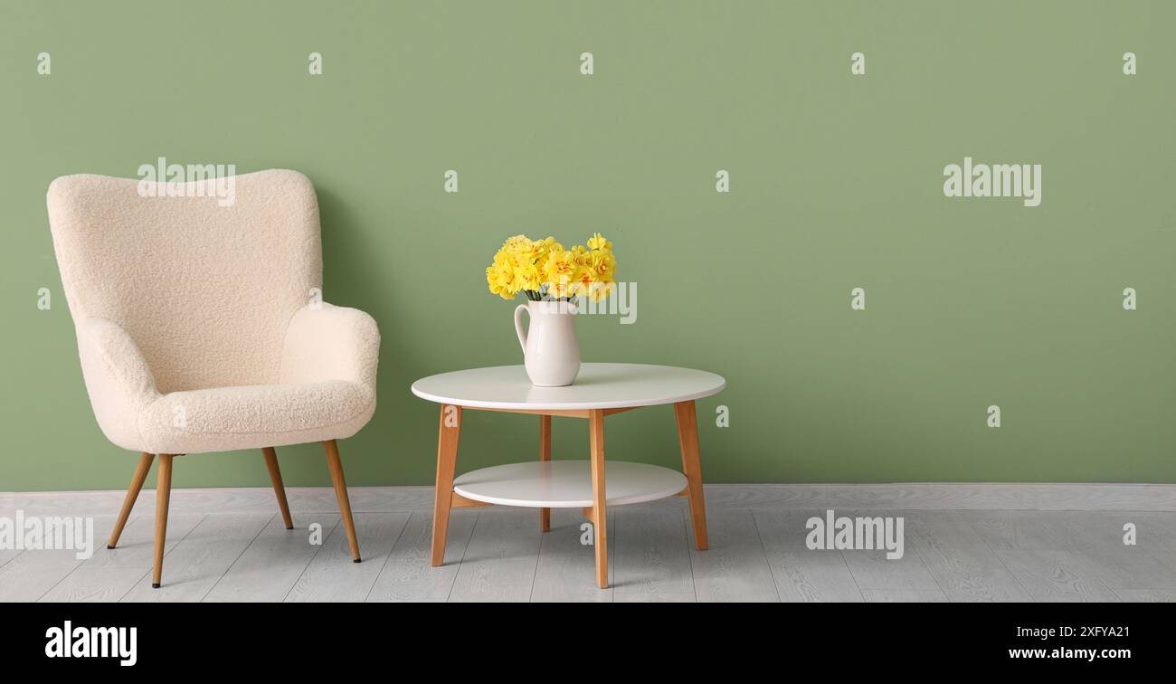 Interior of living room with light armchair, table and daffodil flowers ...