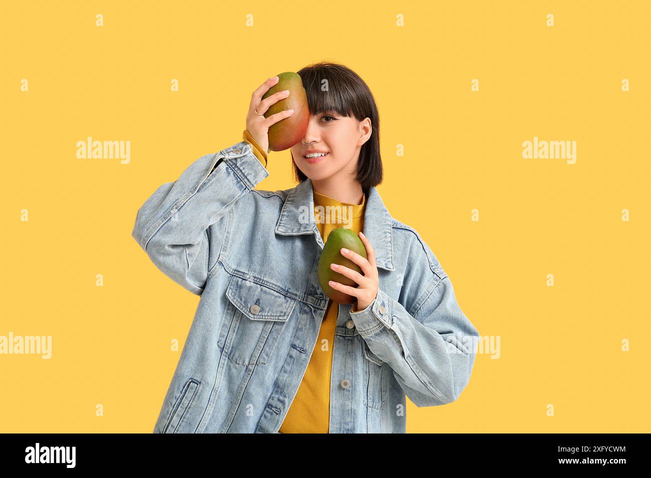 Beautiful young woman with ripe mangoes on yellow background Stock ...