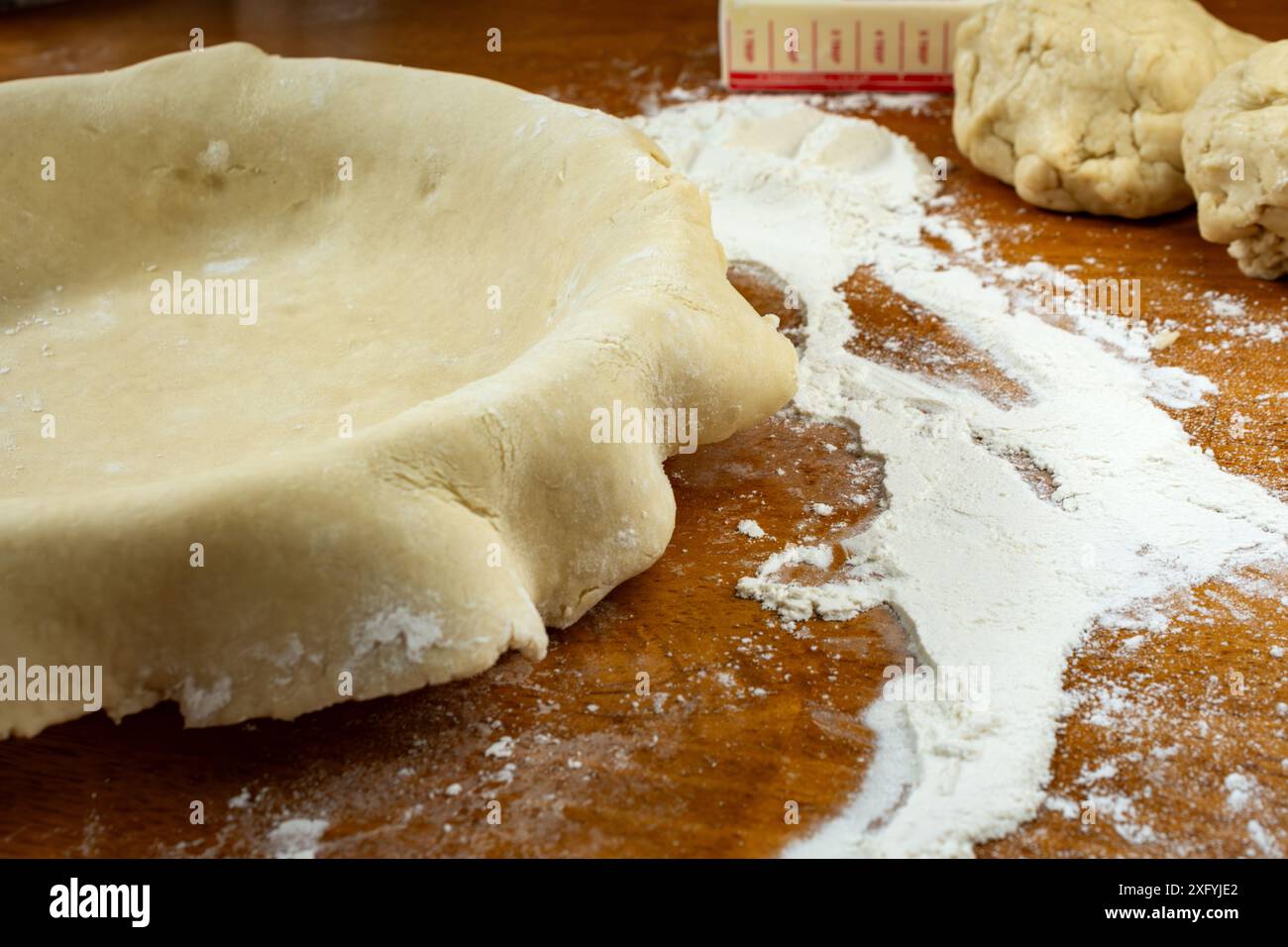 Making a pie. Rolled dough placed over a pie shell. Side view with ...