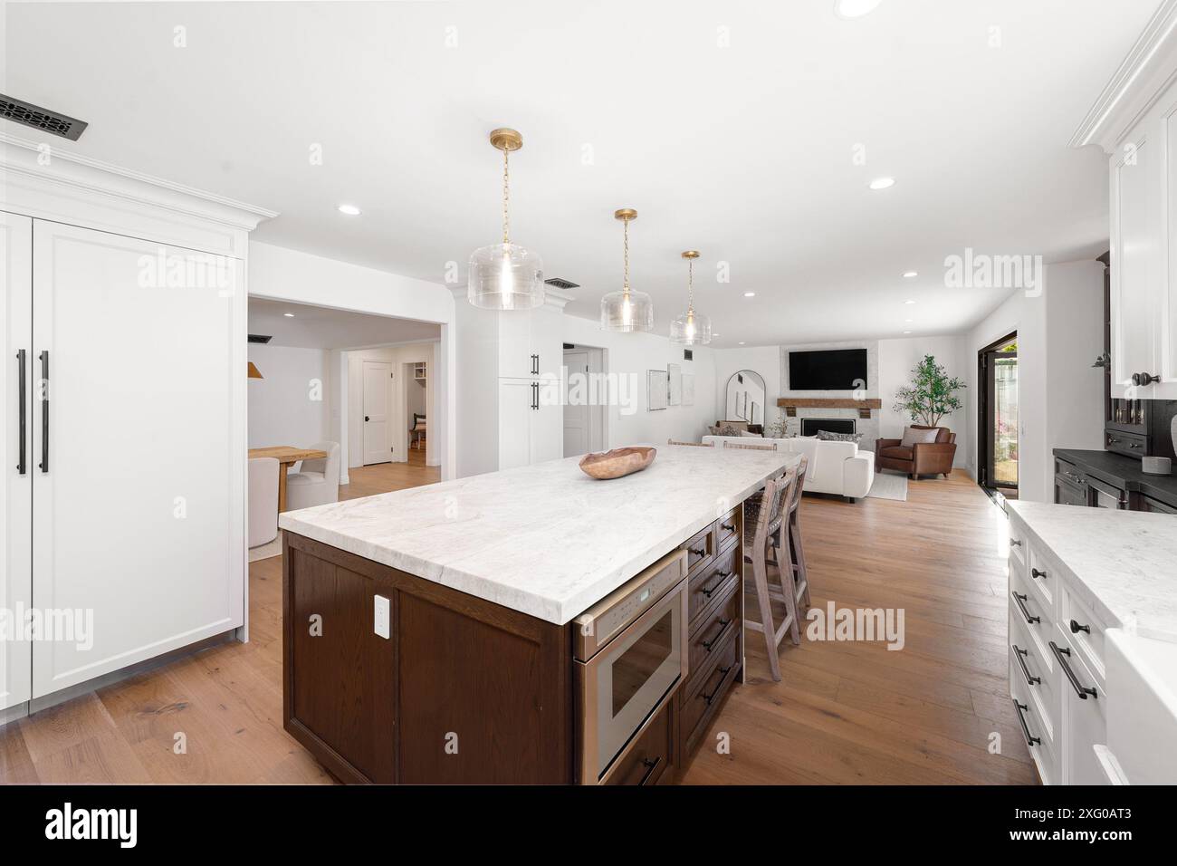 A modern open-concept kitchen and living room with white cabinets ...