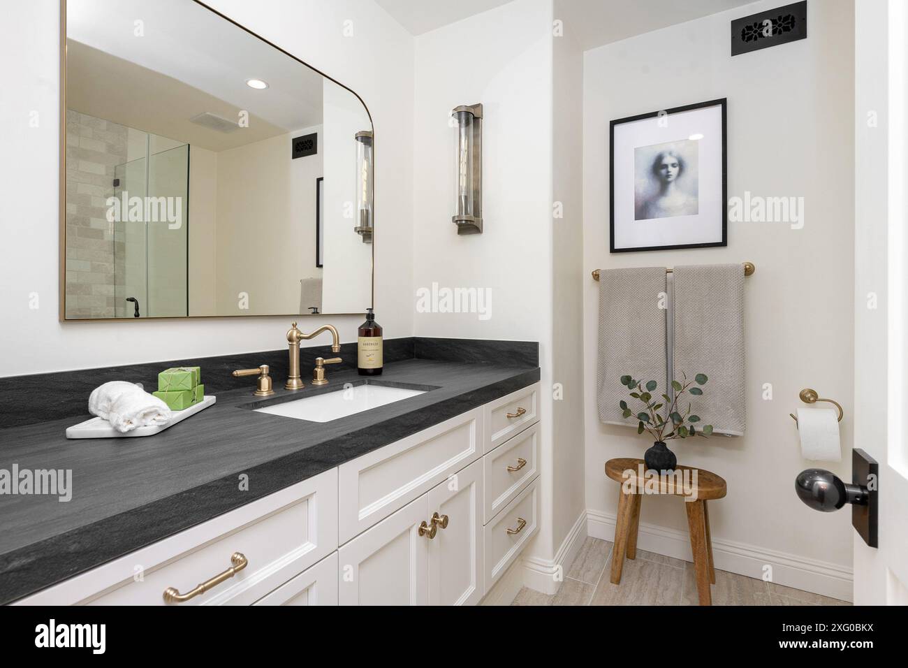 A modern bathroom interior with black countertop, gold fixtures, and a ...
