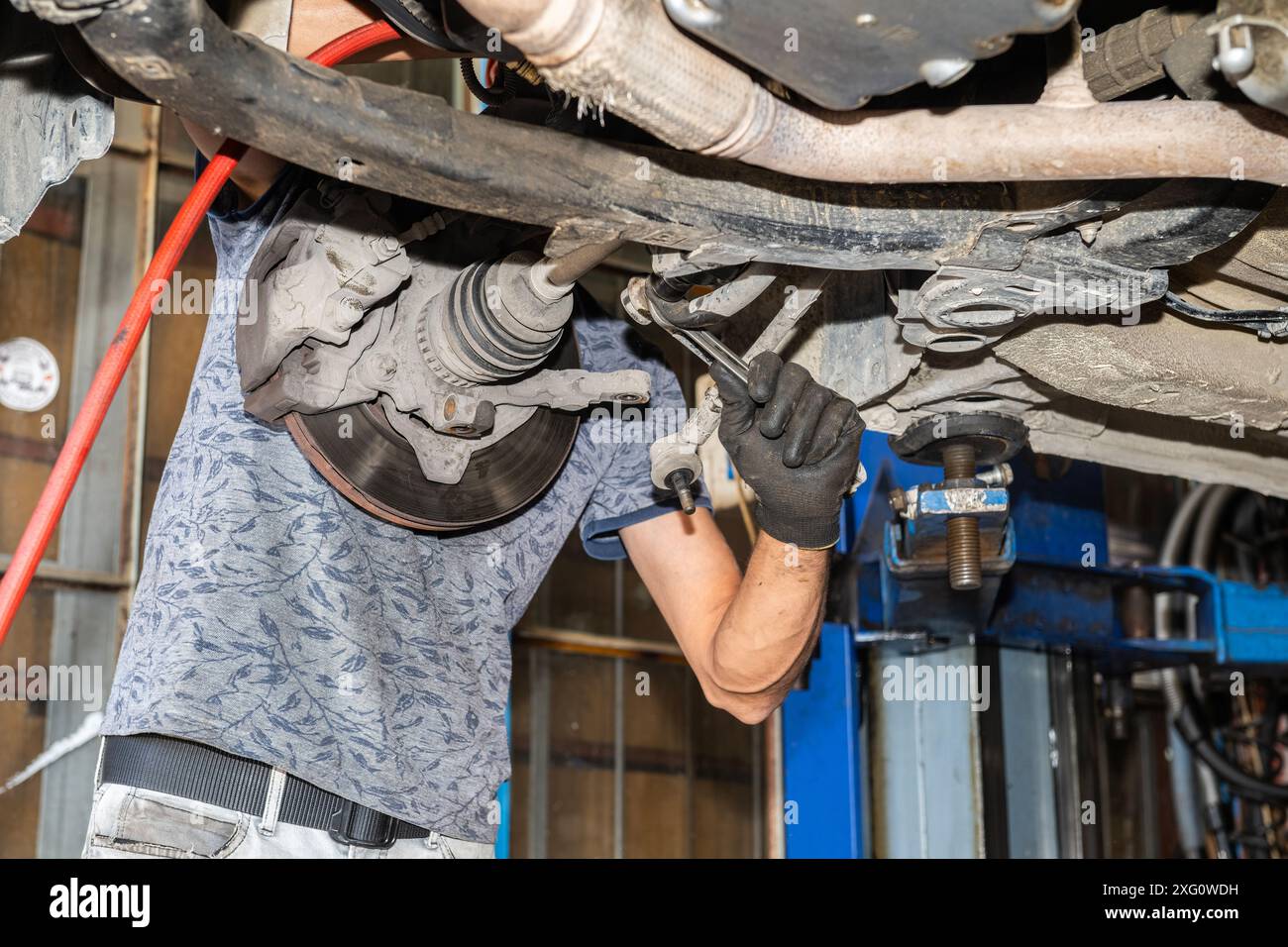 Mechanic repairing car lifted in garage lift Stock Photo - Alamy