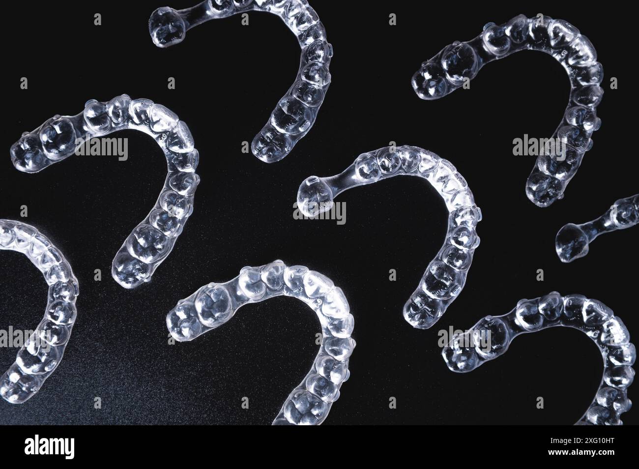 A pattern of invisible plastic aligners lie on a black background Stock ...