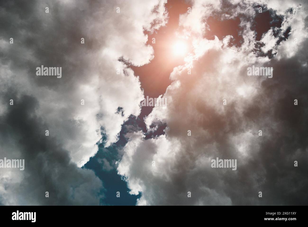 Sun shines through storm clouds, dramatic sky scenery with thunderclouds up above Stock Photo