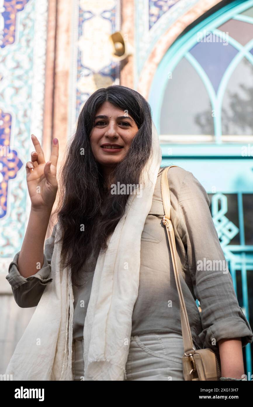 Tehran, Iran. 05th July, 2024. An Iranian woman flashes a victory sign after casting her vote in the presidential runoff election at Hosseinieh Ershad mosque on Friday, July 5, 2024. Iranians began voting on Friday in a runoff election to replace the late President Ebrahim Raisi, who was killed in a helicopter crash last month. (Photo by Sobhan Farajvan/Pacific Press) Credit: Pacific Press Media Production Corp./Alamy Live News Stock Photo