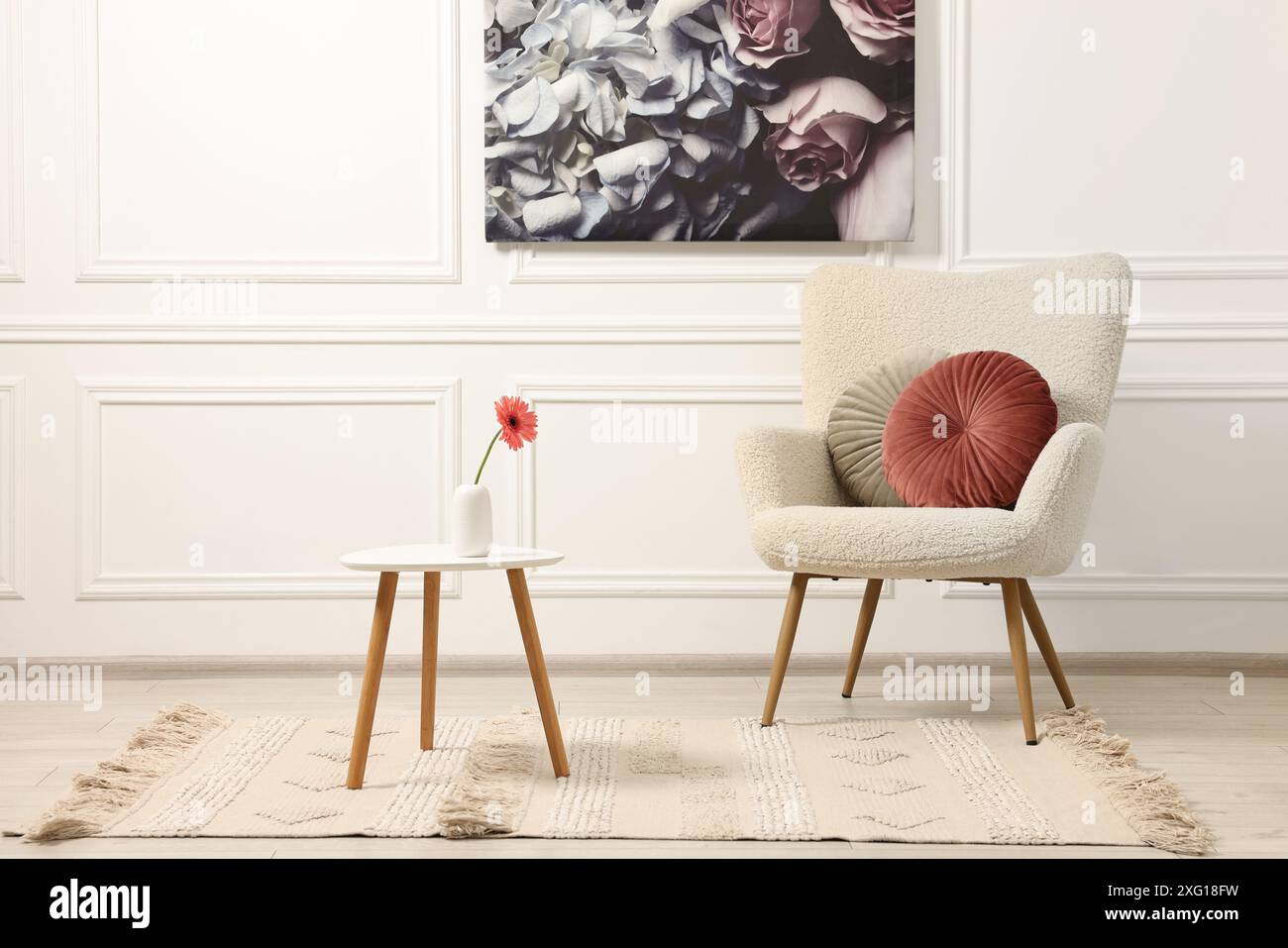 Soft armchair, coffee table with flower and picture in stylish room ...