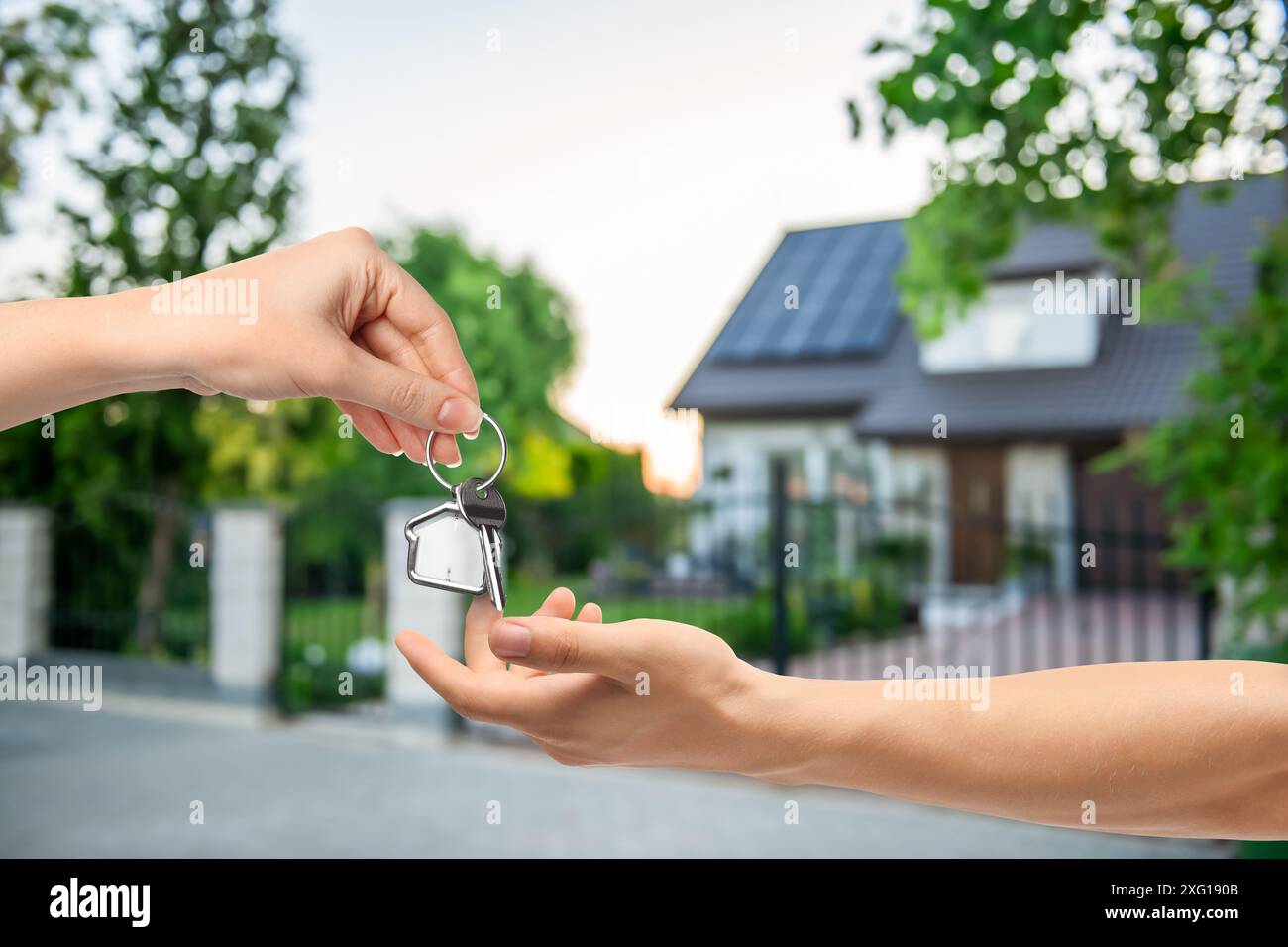 Real estate agent giving house key to new owner against beautiful ...