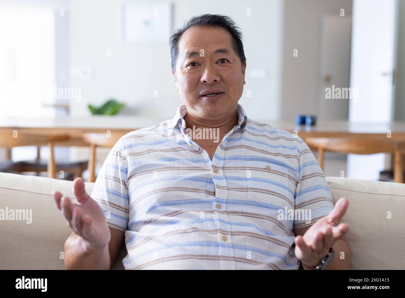 Smiling senior man on video call on couch, enjoying relaxed vacation at home Stock Photo