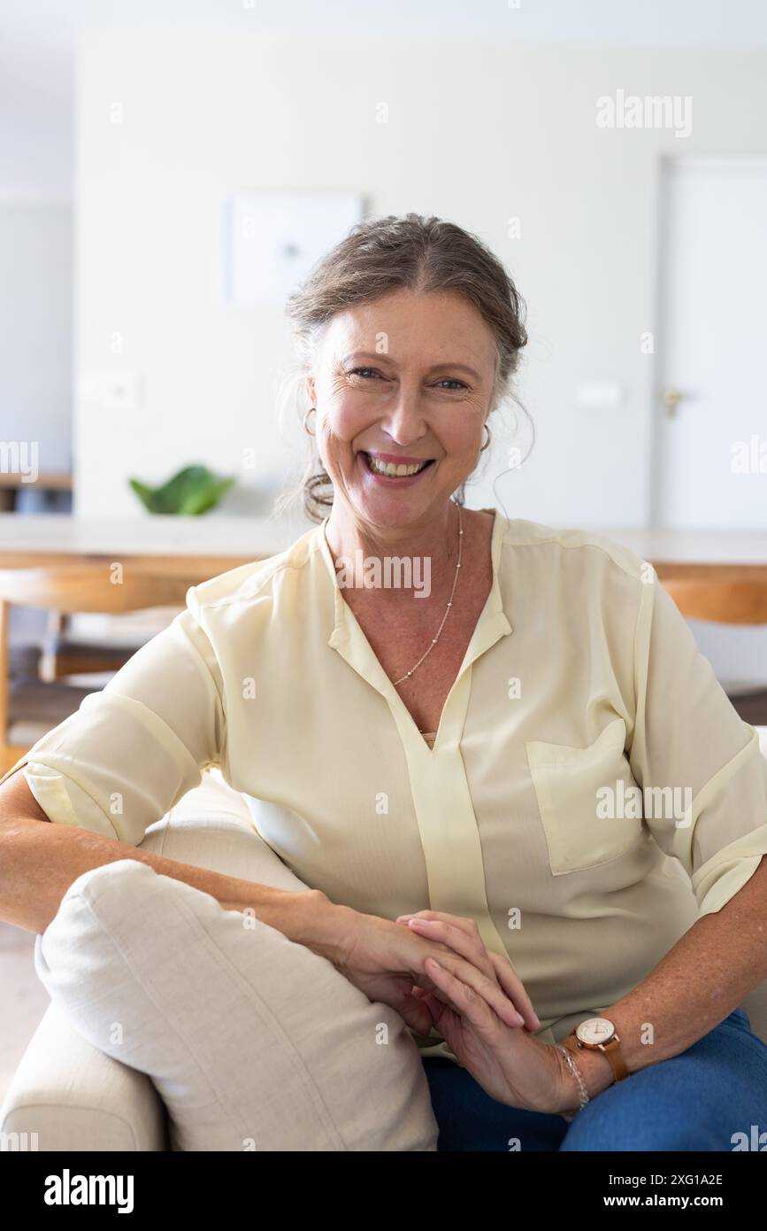 Smiling senior woman sitting on couch, enjoying relaxing vacation at home Stock Photo