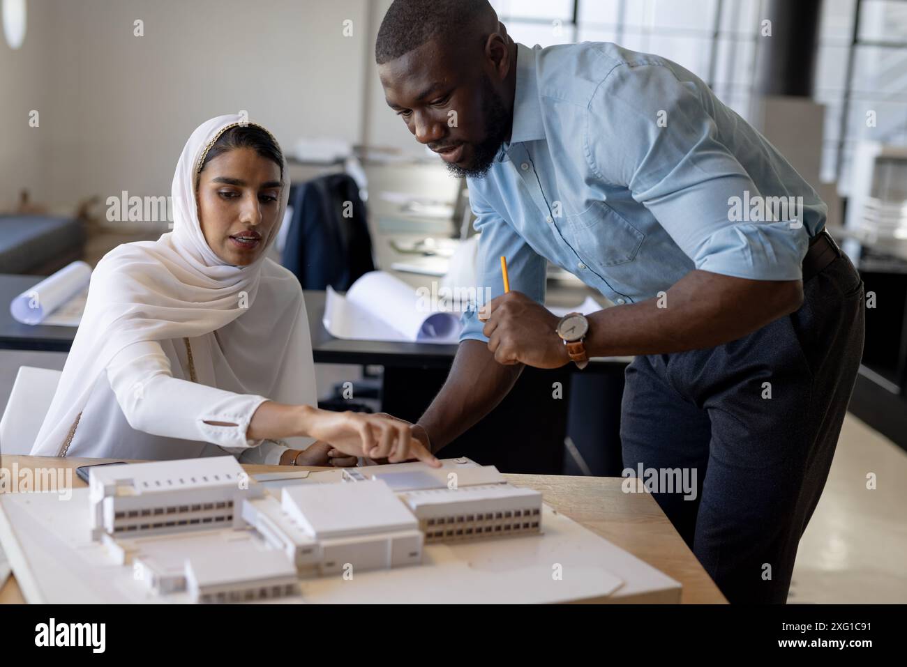 Architects discussing building model, collaborating on project in modern office Stock Photo