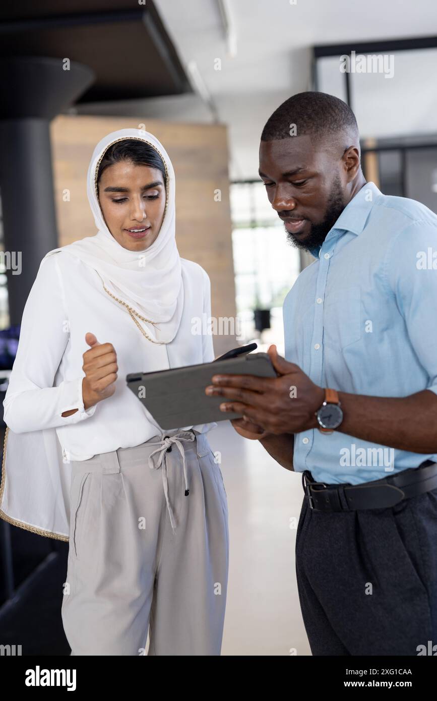 Discussing project details, business colleagues using tablet in modern office Stock Photo